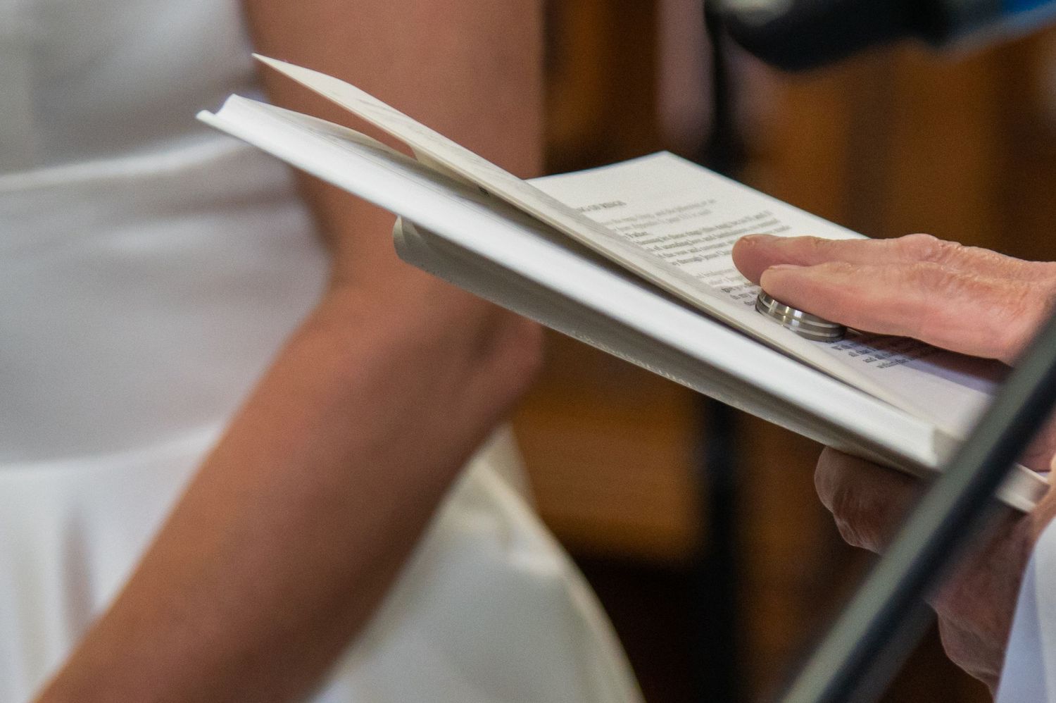 Close-up shot of hands signing documents during a wedding ceremony.