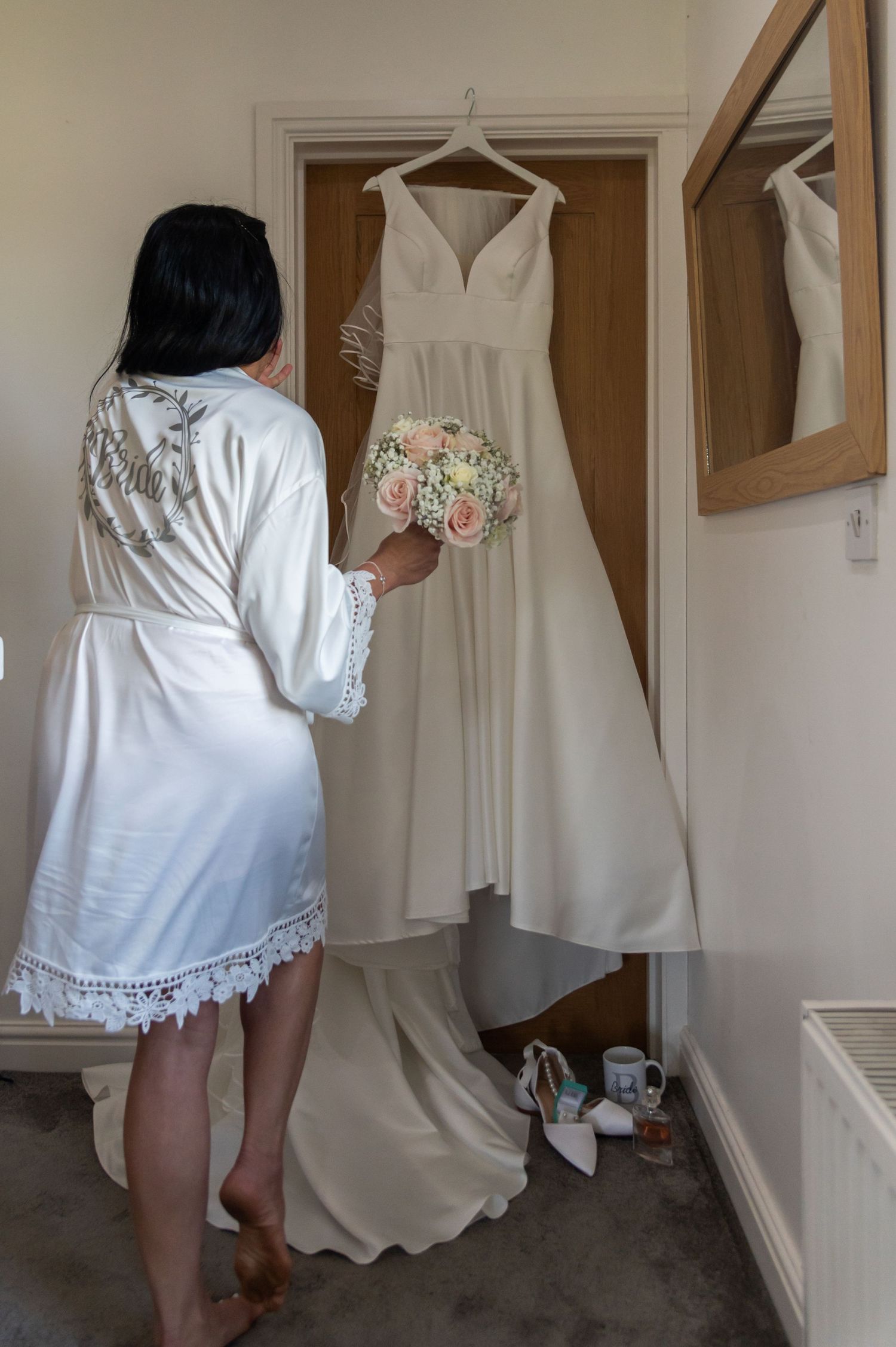 Various white wedding dresses and gowns hanging on display in a room with beige walls.