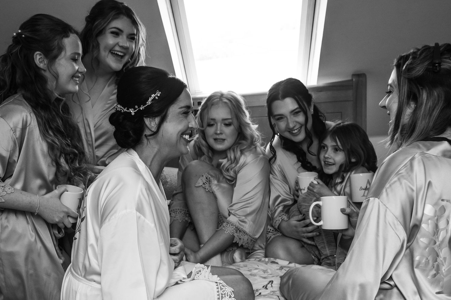 Wedding party members share joyful laughter together in a candid black and white photographic sequence.