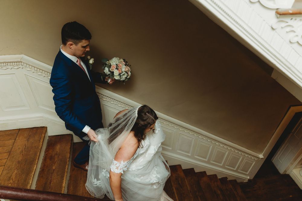 Couple descending a staircase in formal wedding attire.