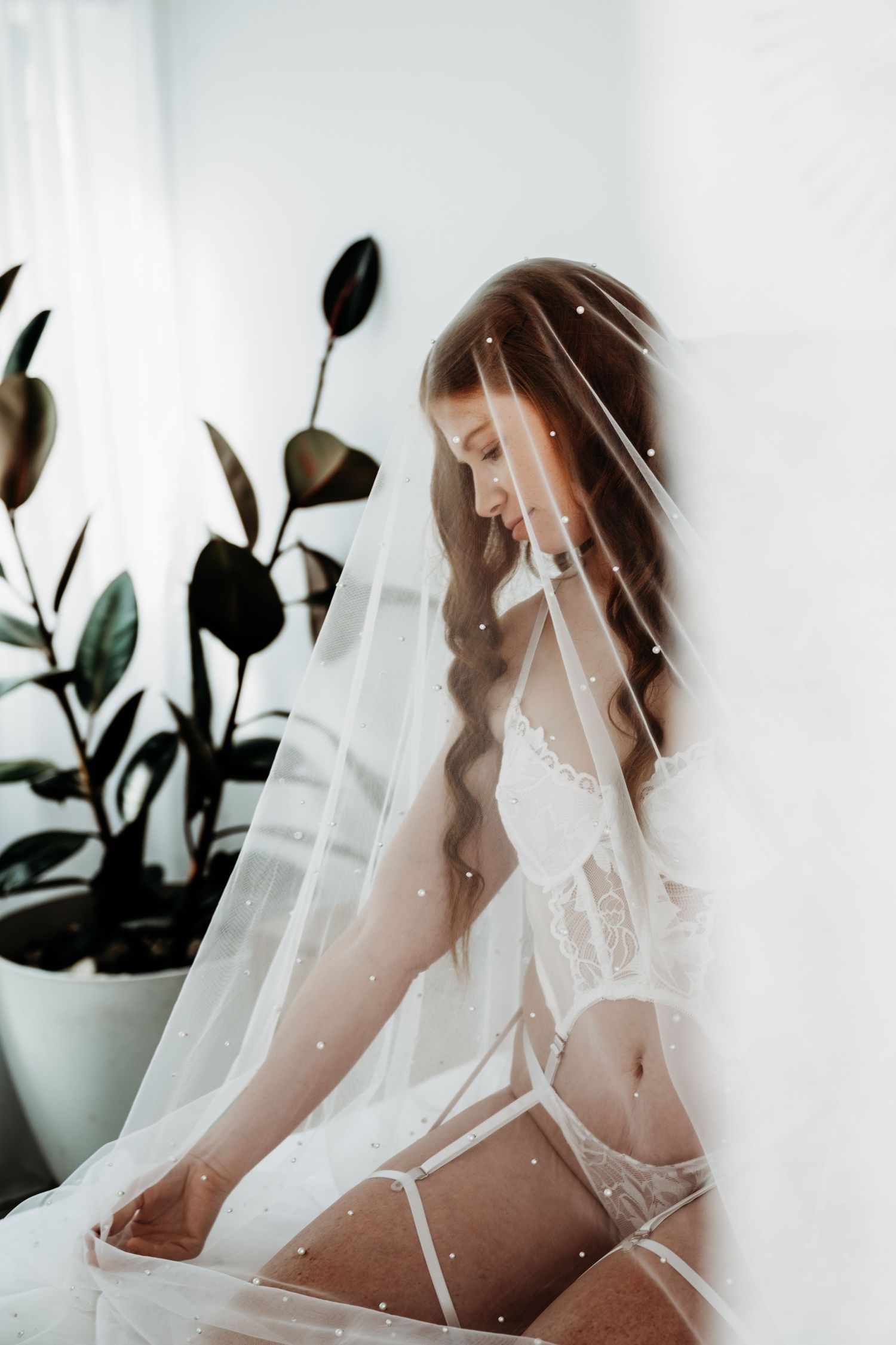 Ethereal bridal boudoir photo with soft white veil and lingerie.