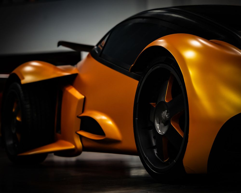 Sleek orange and black sports car showcased in dramatic low-key studio lighting.