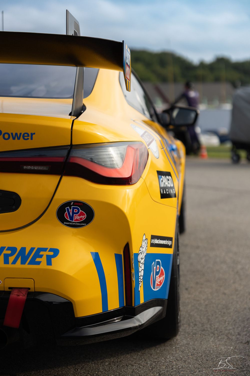 Close-up rear view of a yellow Turner Motorsport race car with a large spoiler at a racing circuit.