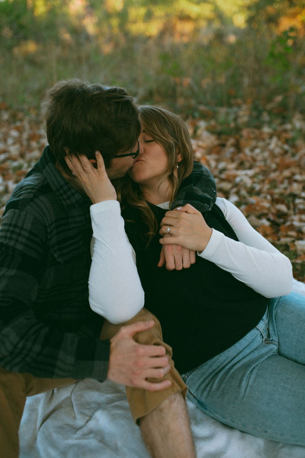 Tender embrace photographed among fallen autumn leaves in a wooded setting.