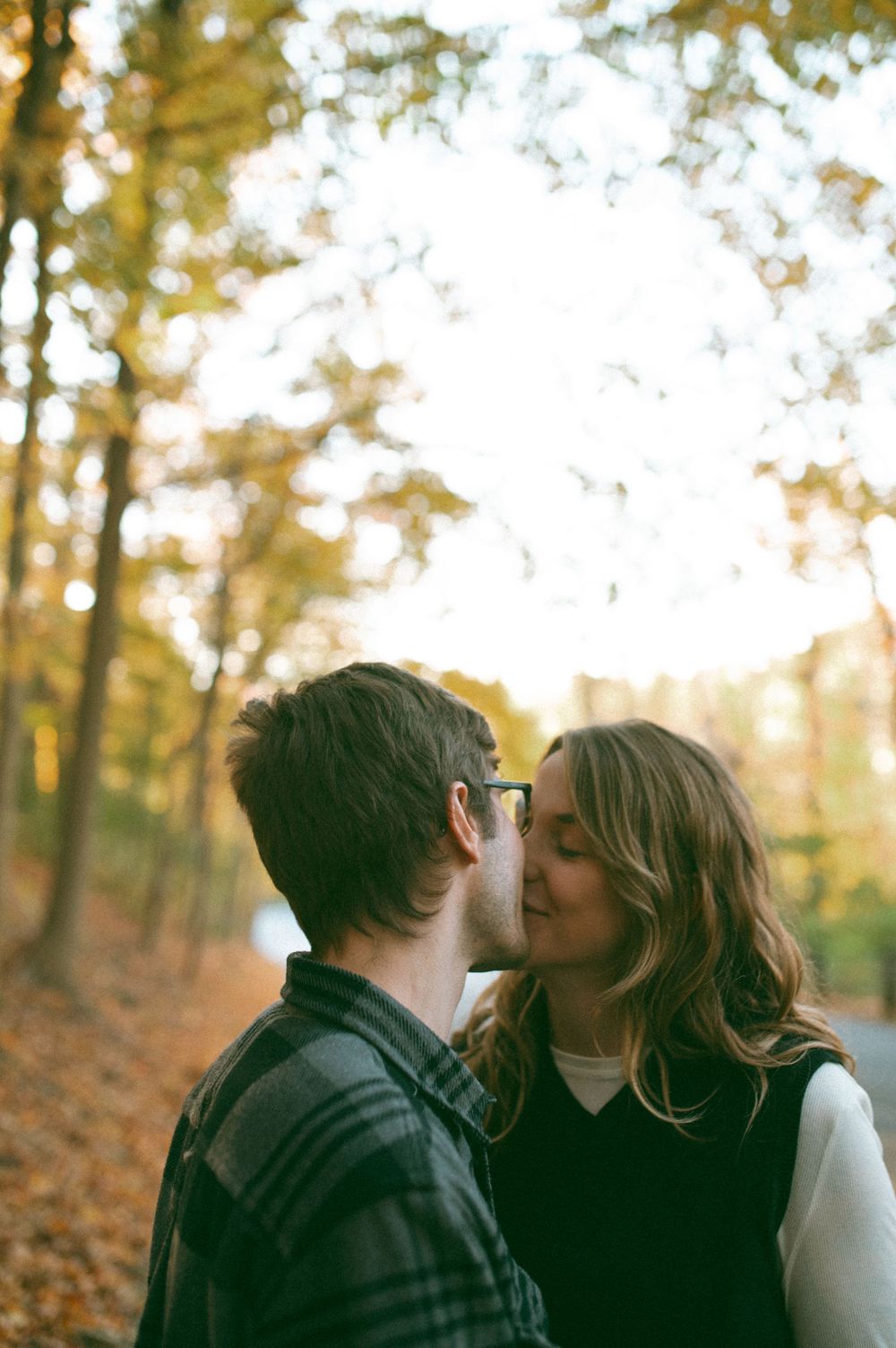Intimate moment captured in a forest during golden hour with autumn foliage.