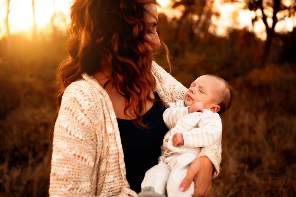 Parent and infant sharing a tender moment in warm sunset lighting.