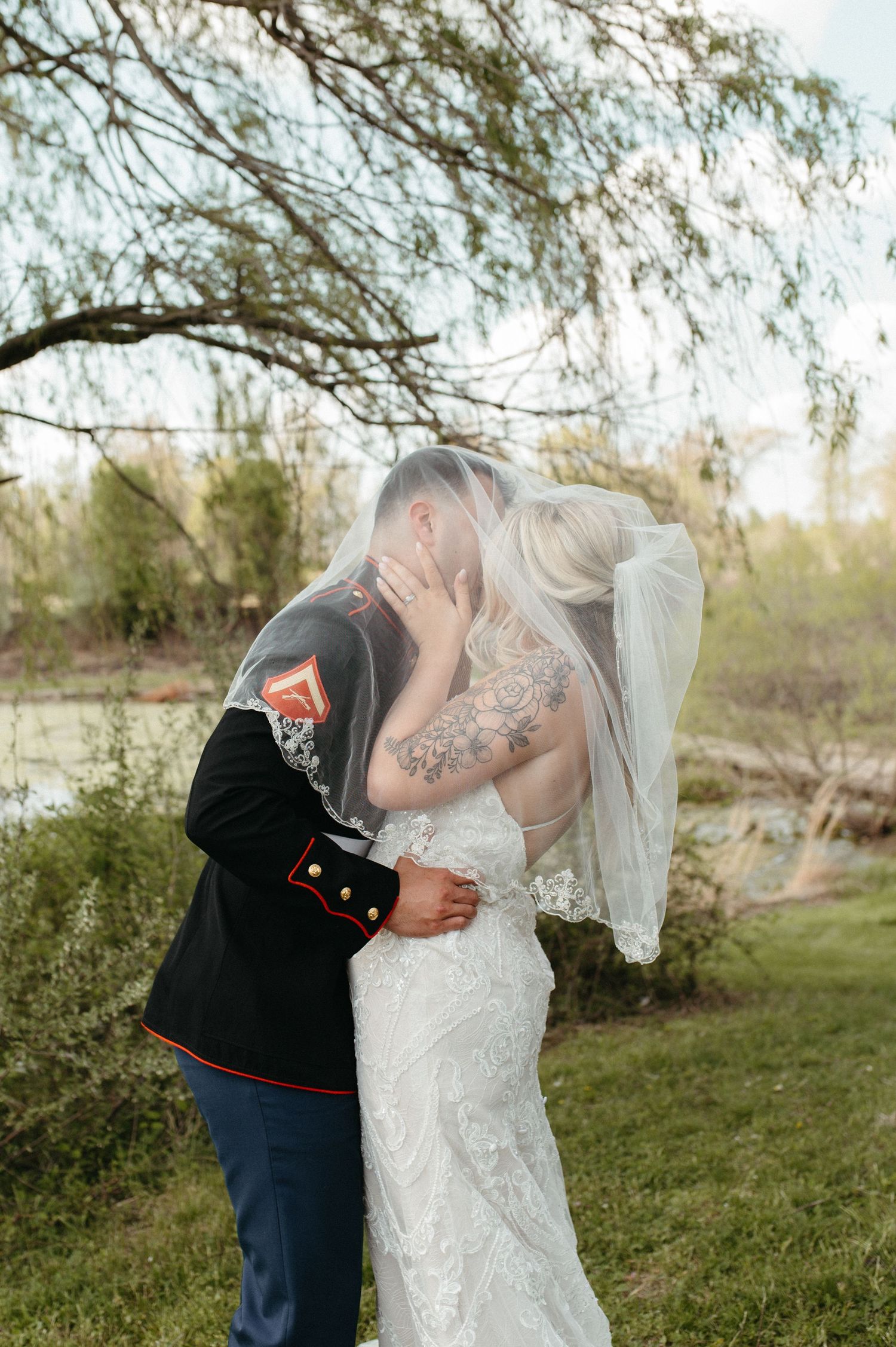 A romantic outdoor wedding portrait with a willow tree backdrop.
