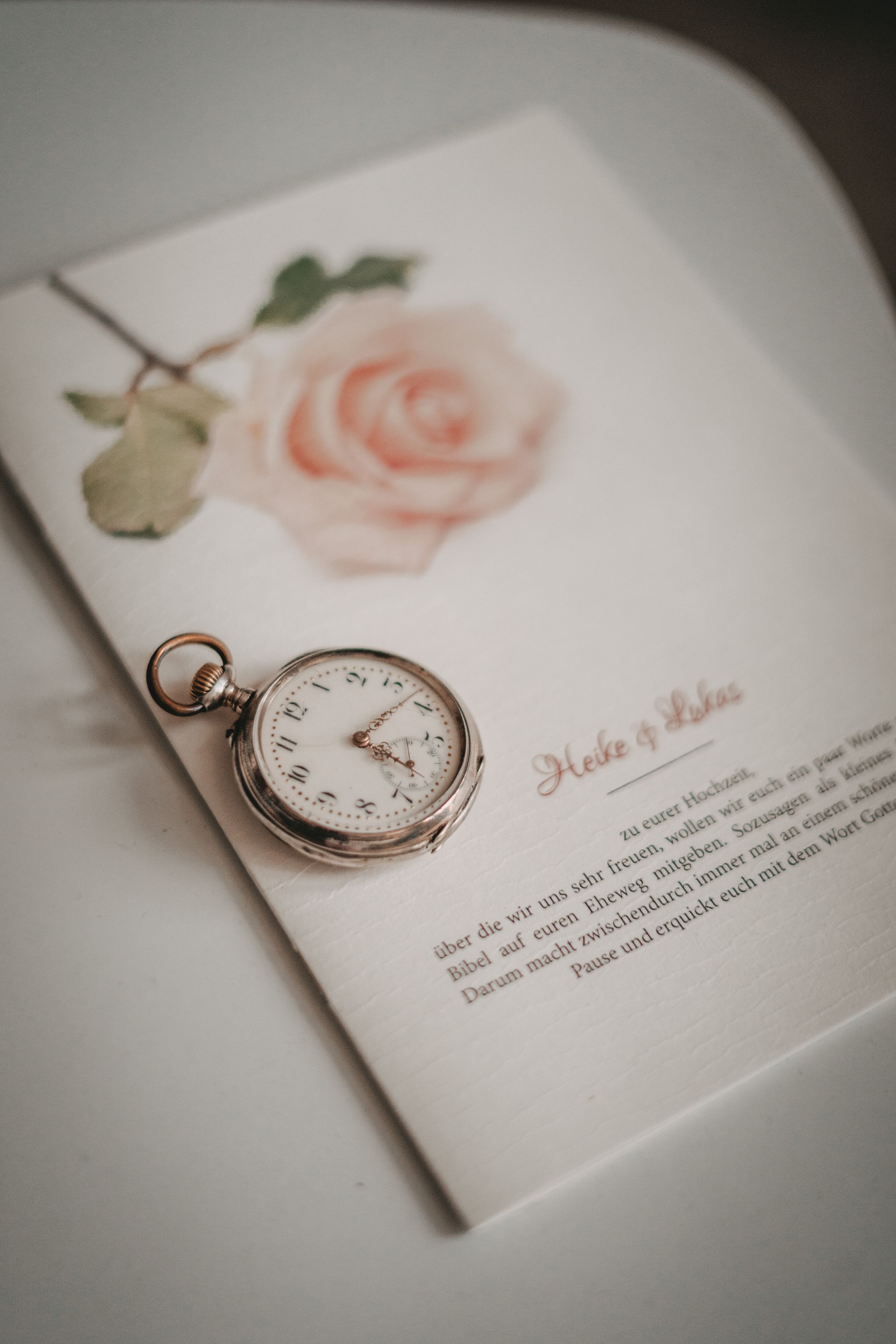 Vintage pocket watch on wedding invitation with watercolor rose design.
