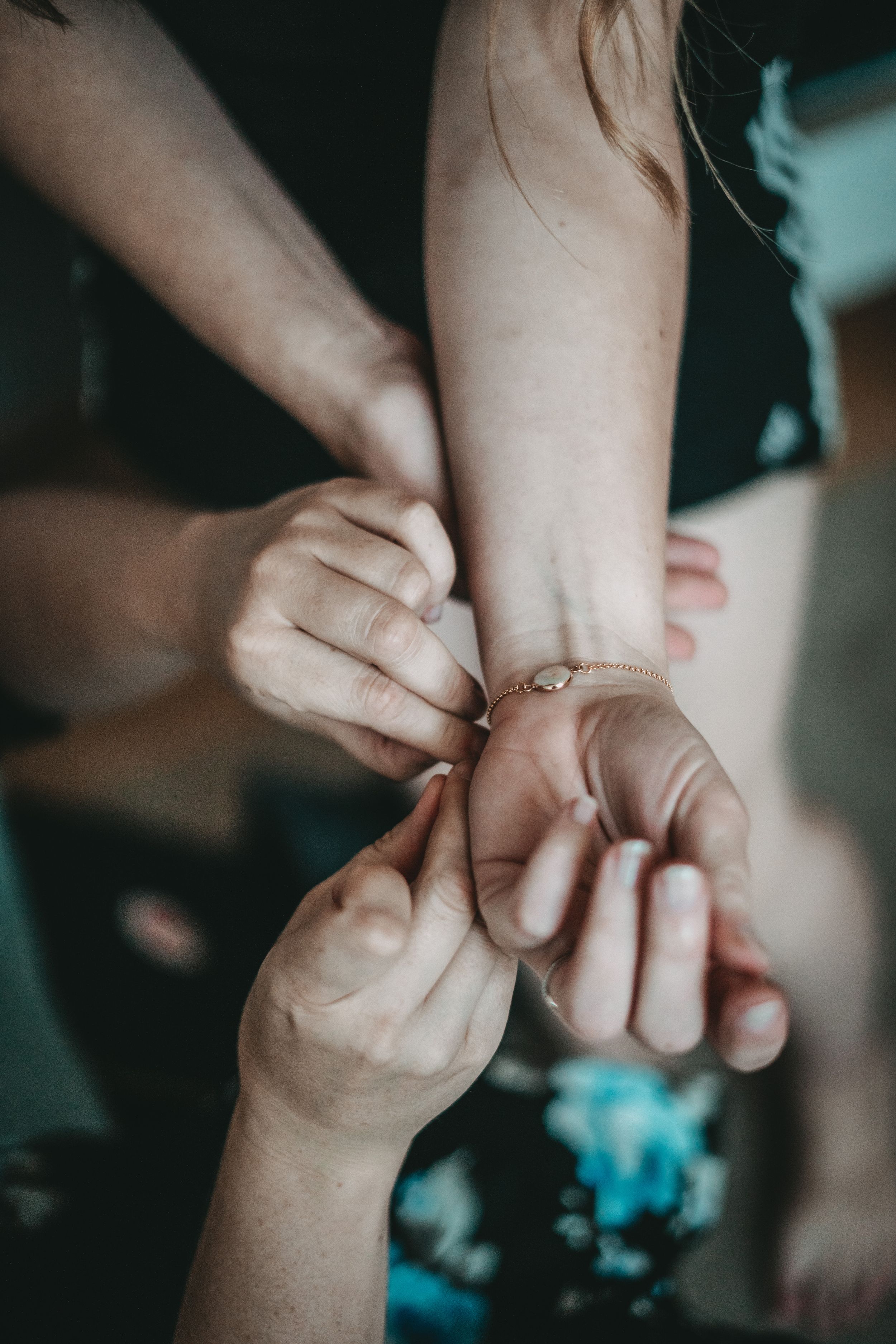 Close-up of hands fastening bracelet or jewelry on wrist during wedding preparations.