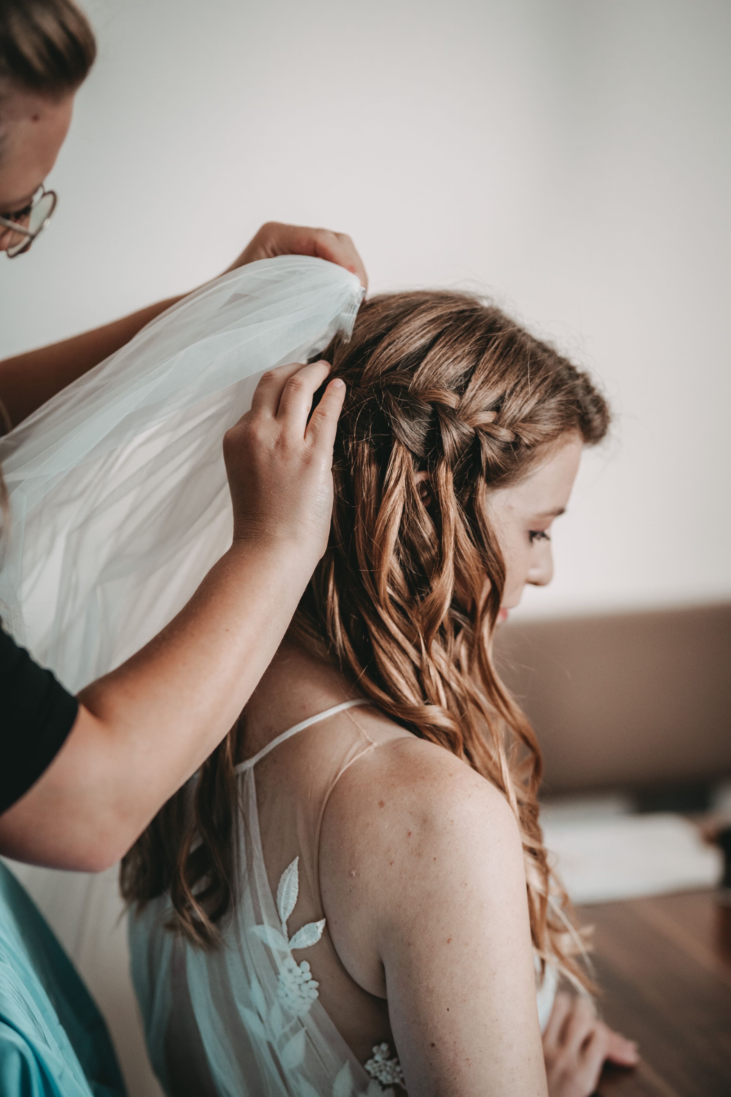 Close-up of a bride getting her veil adjusted while showing intricate braided hairstyle.