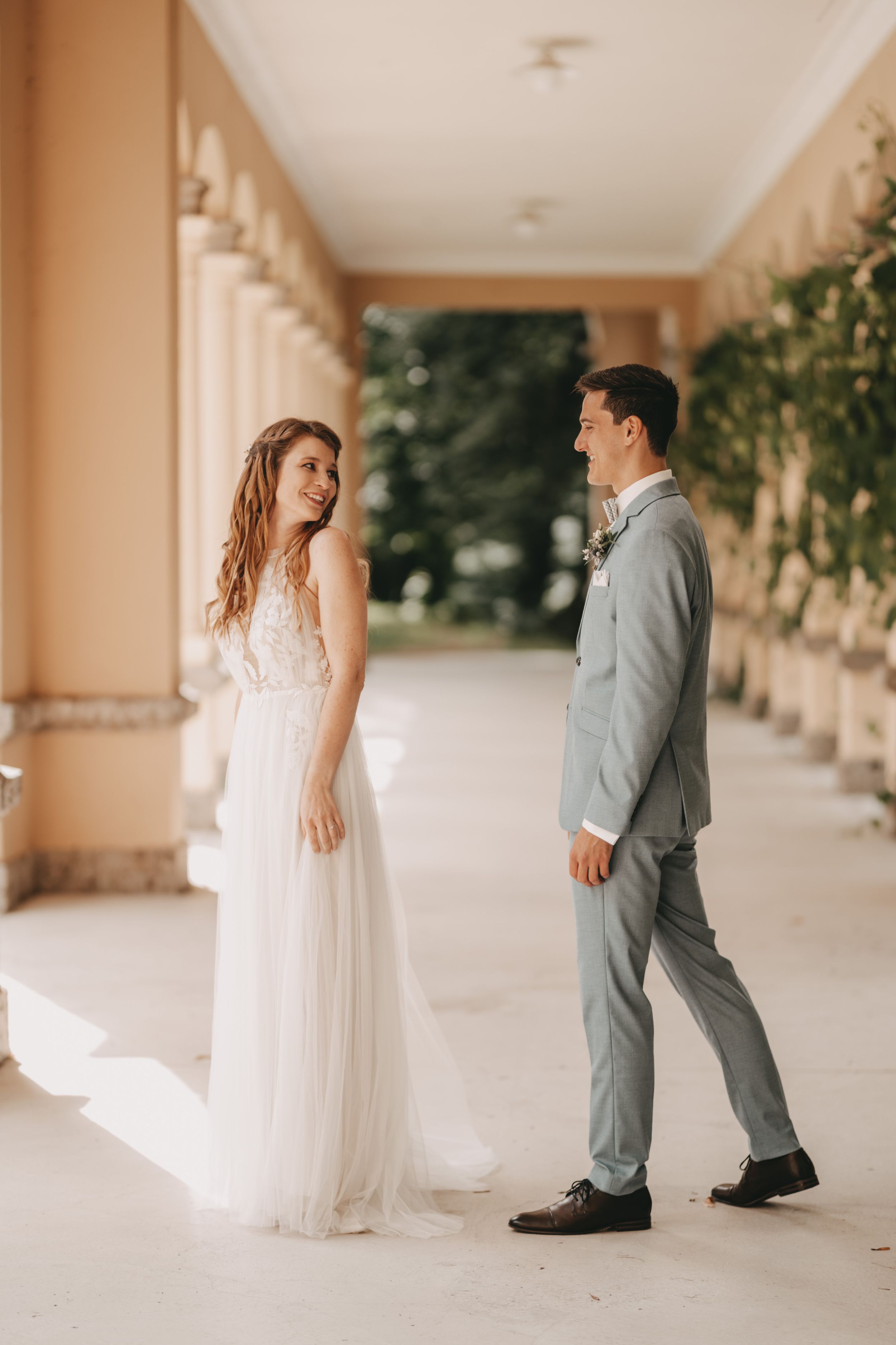 Candid sequence of wedding couple's first look in columned walkway.