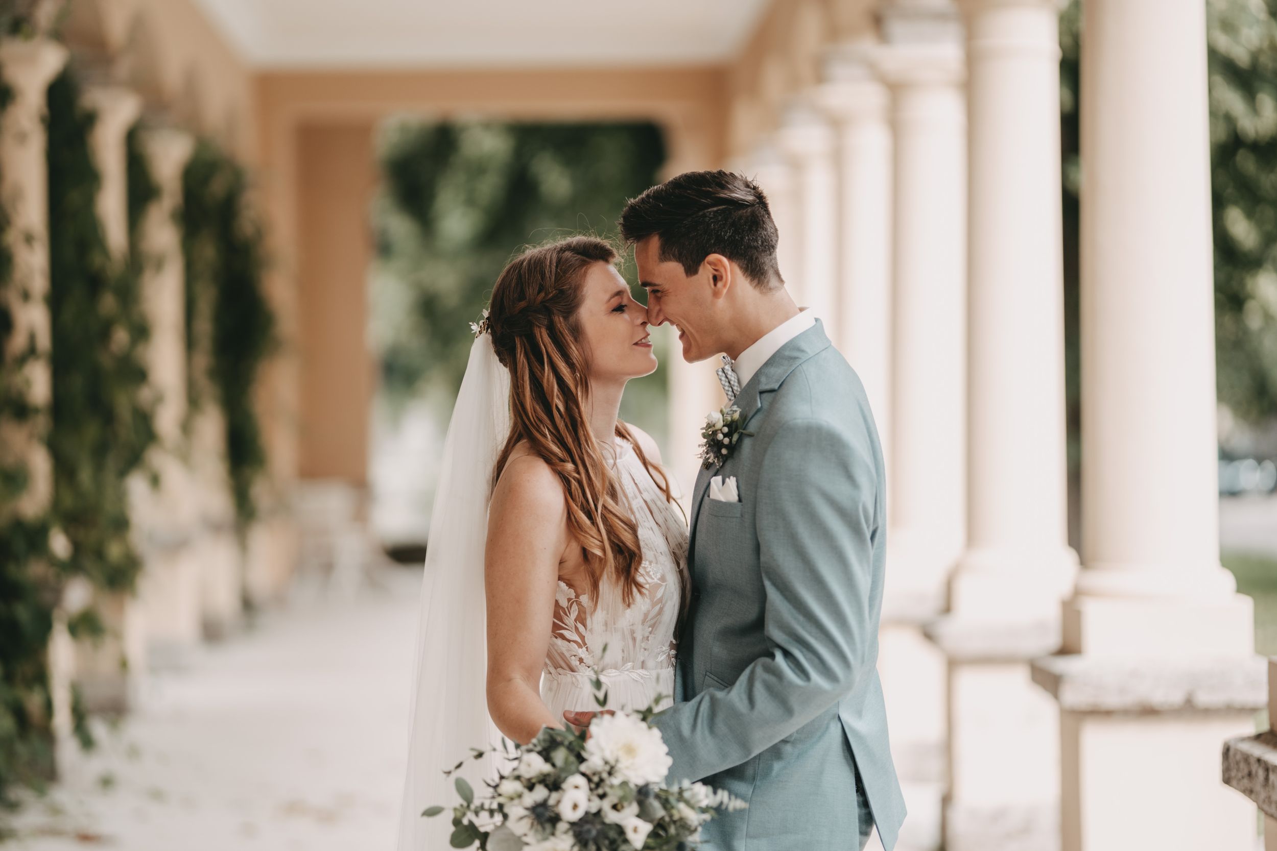 Wedding couple shares tender moments along a beautiful columned walkway.
