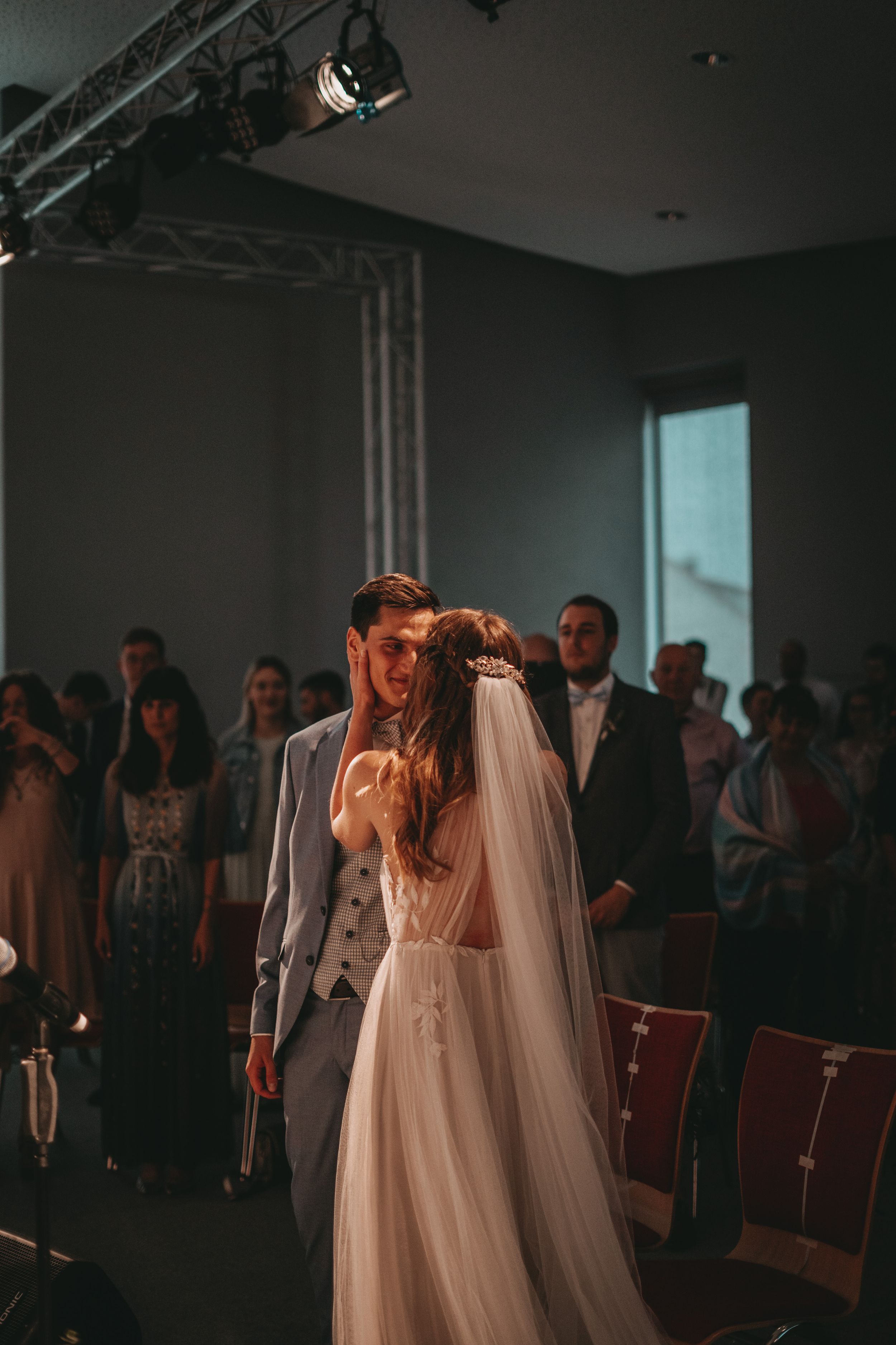 A couple dancing at their wedding reception under dramatic stage lighting.