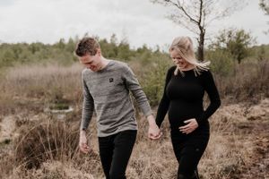 Stel loopt met hun handen vast tijdens een zwangerschapsshoot