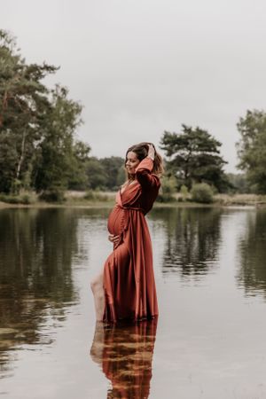 Zwangere vrouw in het water met prachtige rode jurk