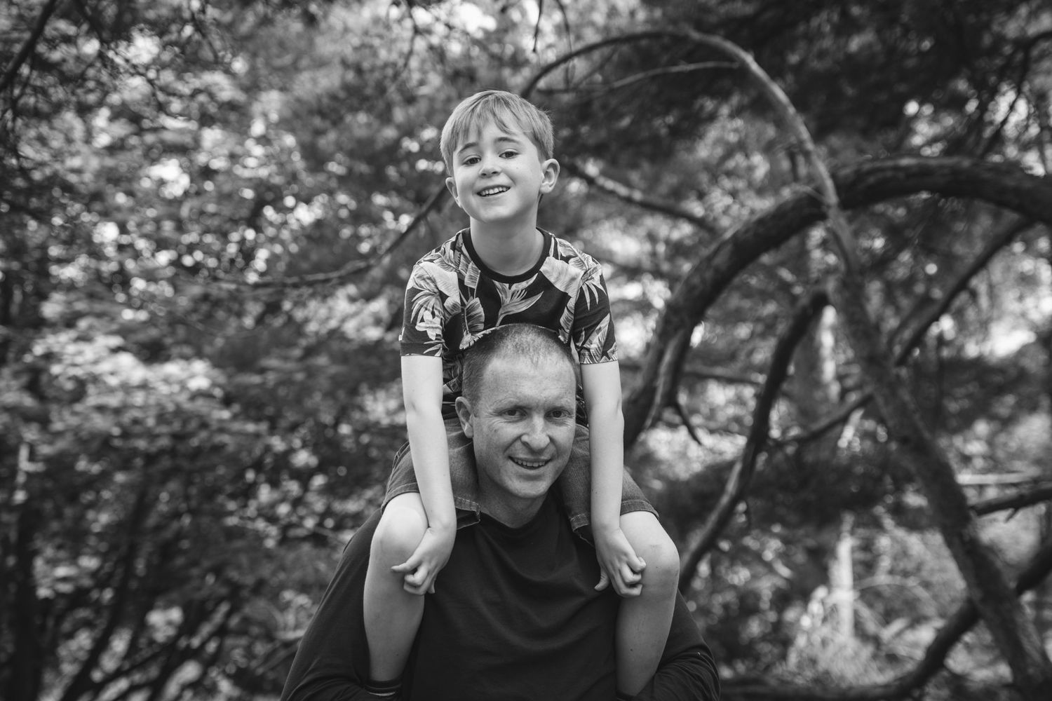 A joyful moment captured in black and white among trees in a forest setting.