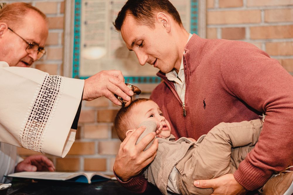 Baby in beige outfit being held and entertained.