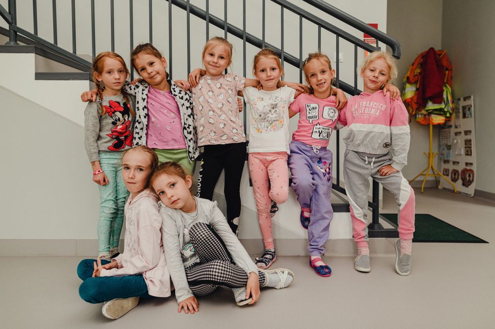 Children sitting in a row along a staircase during a dance class break.