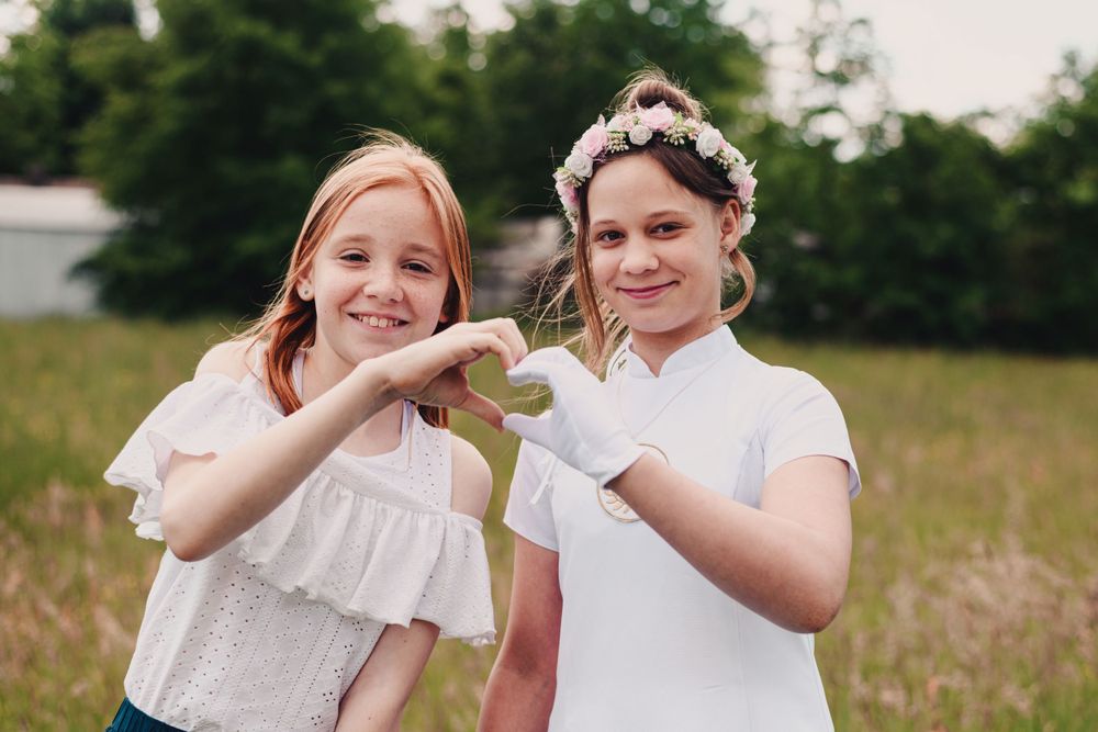 Two children in white dresses playing in a summer field.