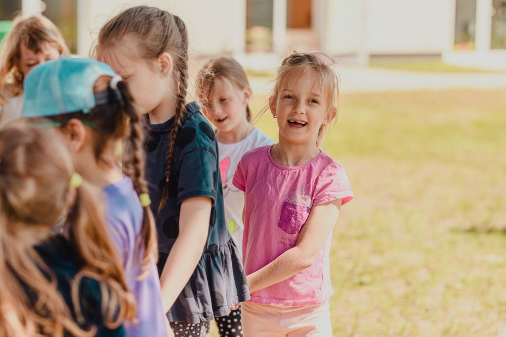 Group of children participating in an outdoor dance class on a sunny day.