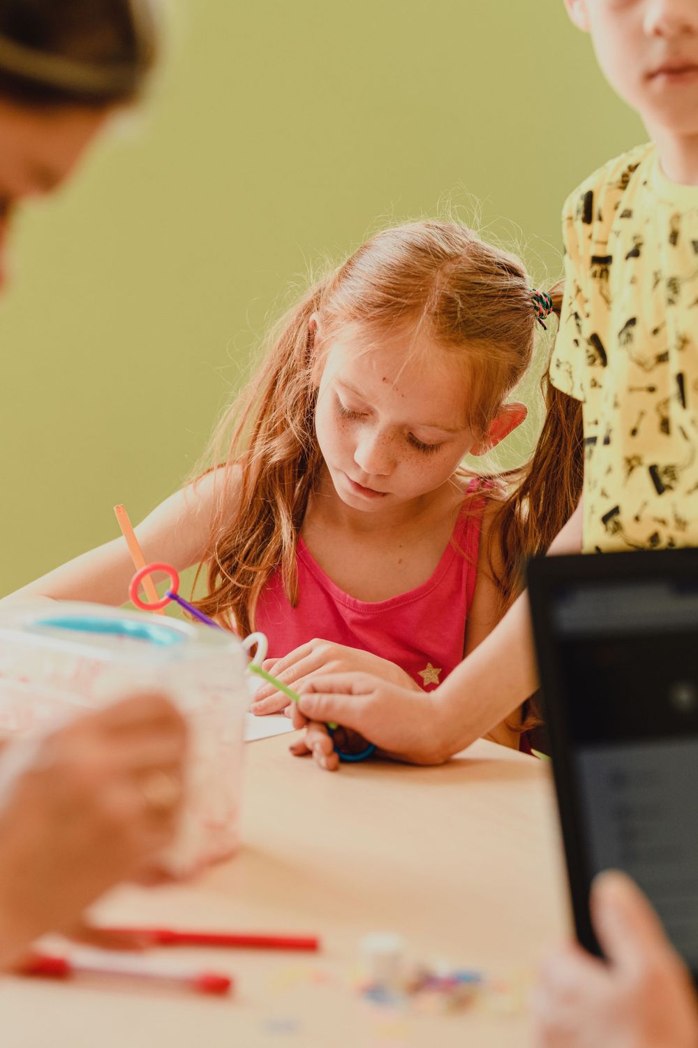Child focused on creative activity at table with art supplies.
