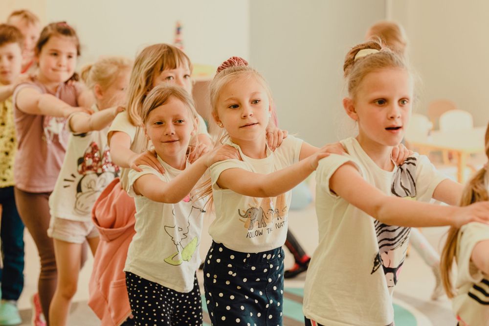 Young children in dance class performing ballet moves together in a bright studio space.
