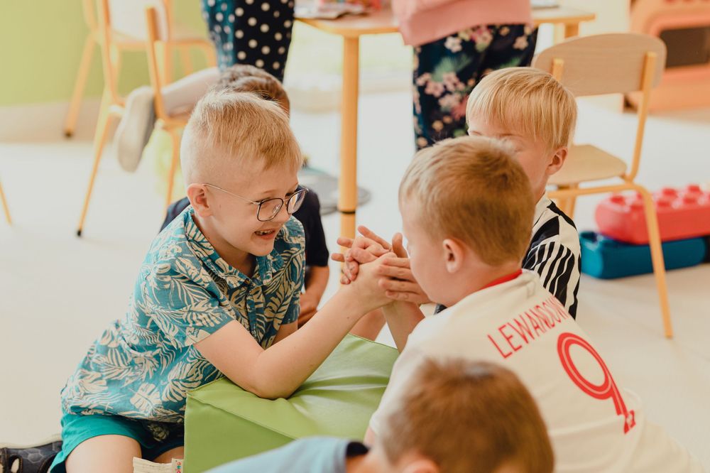 Children sitting at classroom table engaged in learning activities.