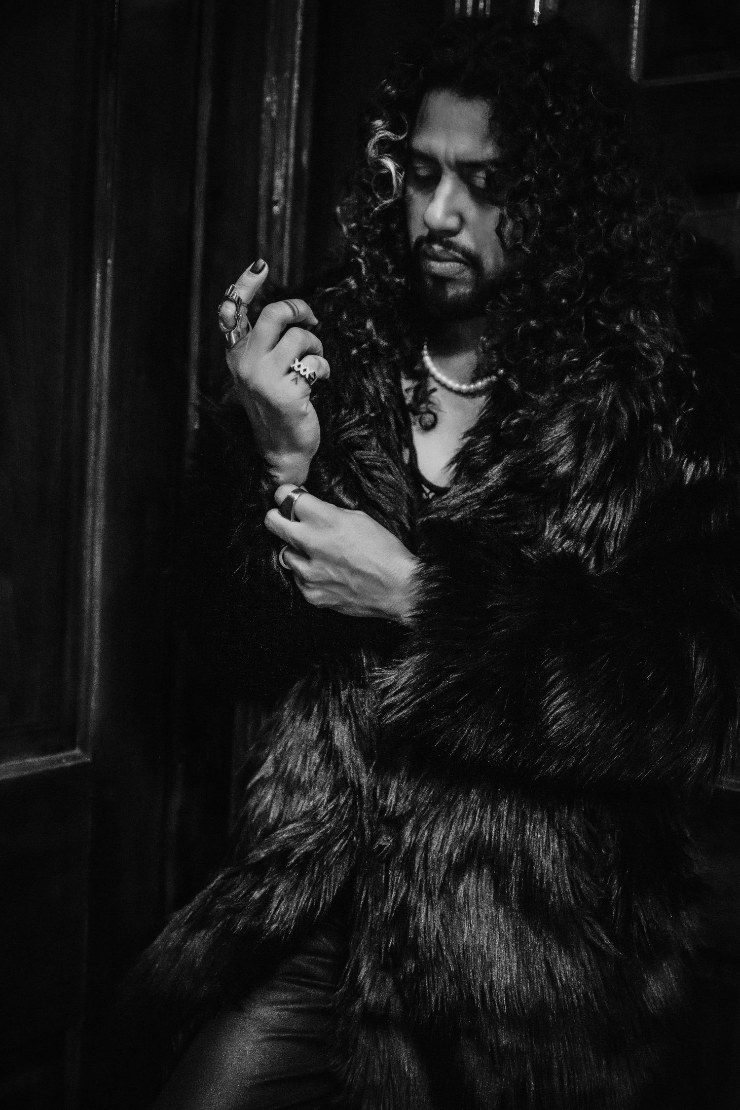 Dramatic portrait of someone wearing a fur coat in dark, moody lighting.