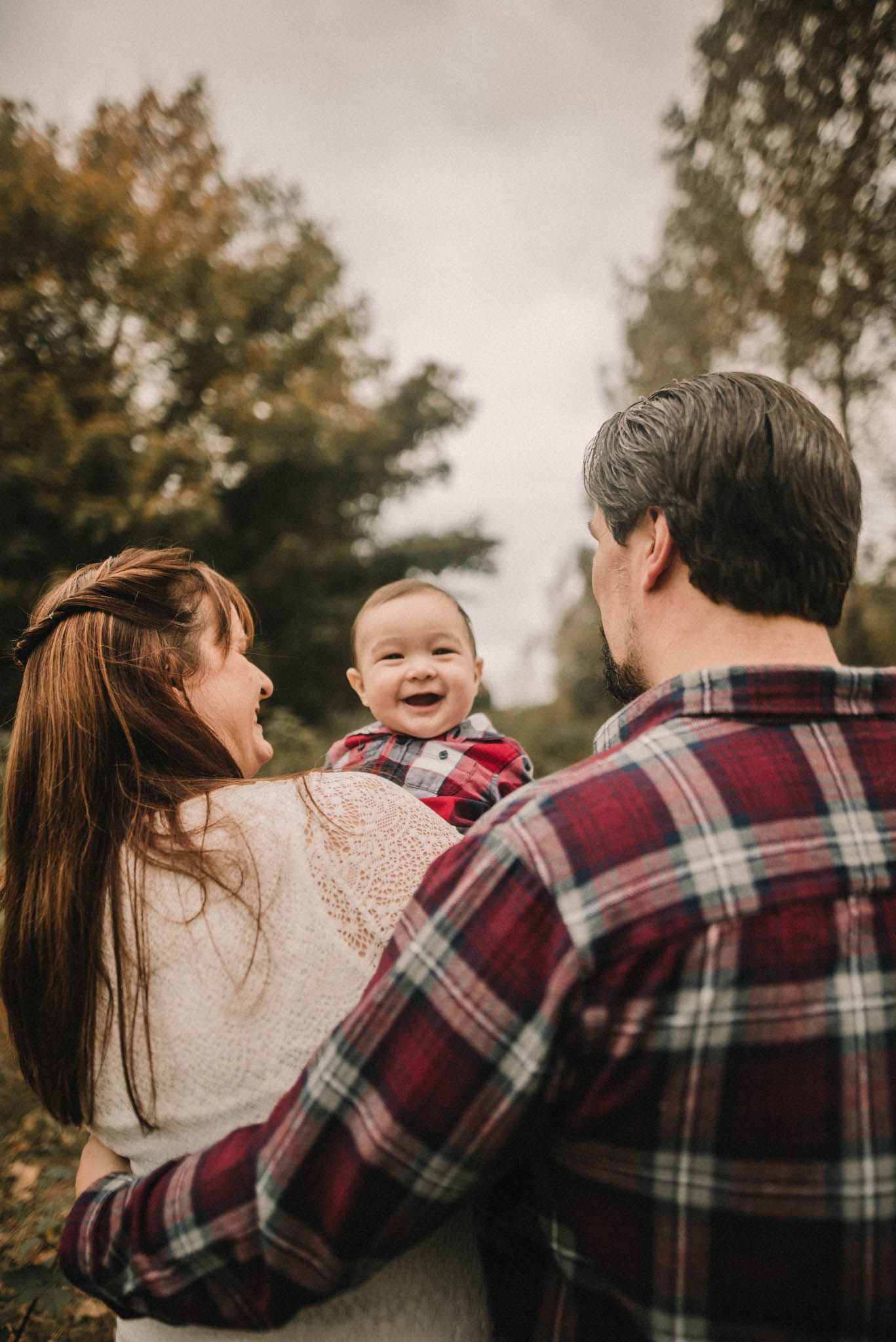 A happy family shares a joyful moment together outdoors while holding their laughing baby.