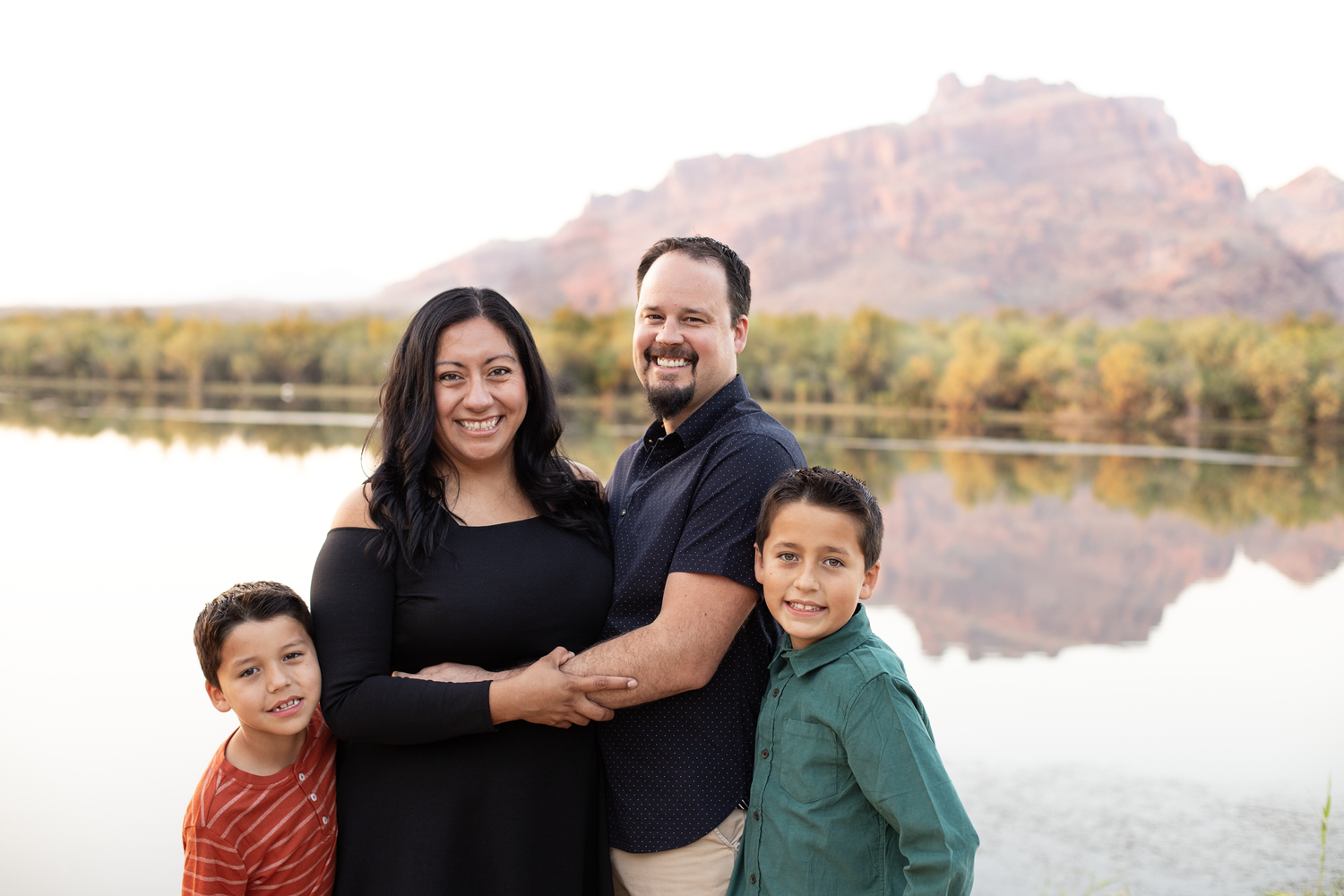 Family portrait session by lakeside with mountains visible in background.