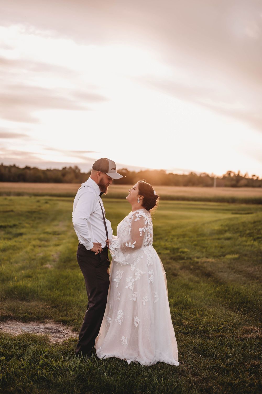 A couple shares an intimate moment in a field at sunset during their wedding day.