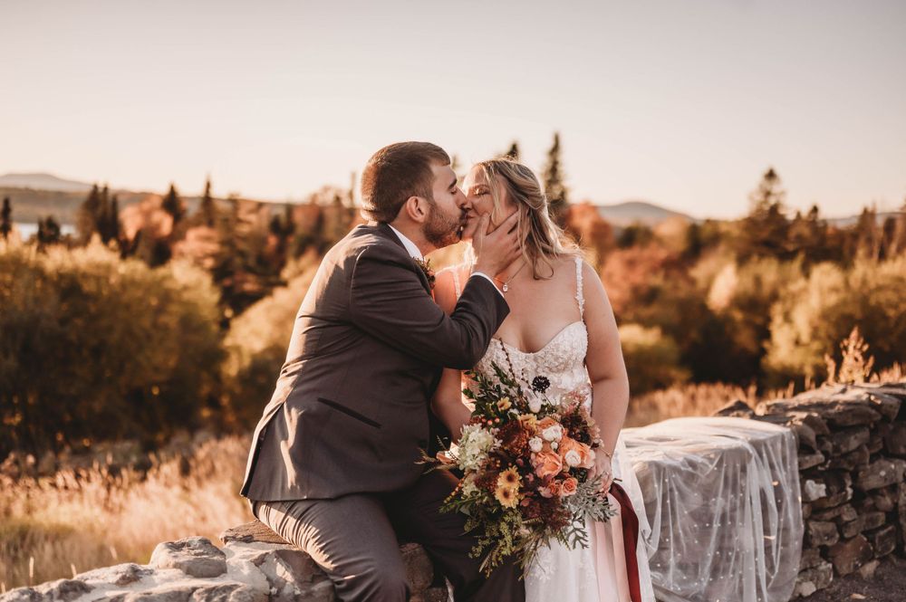 Intimate wedding moment captured during sunset with autumn landscape.
