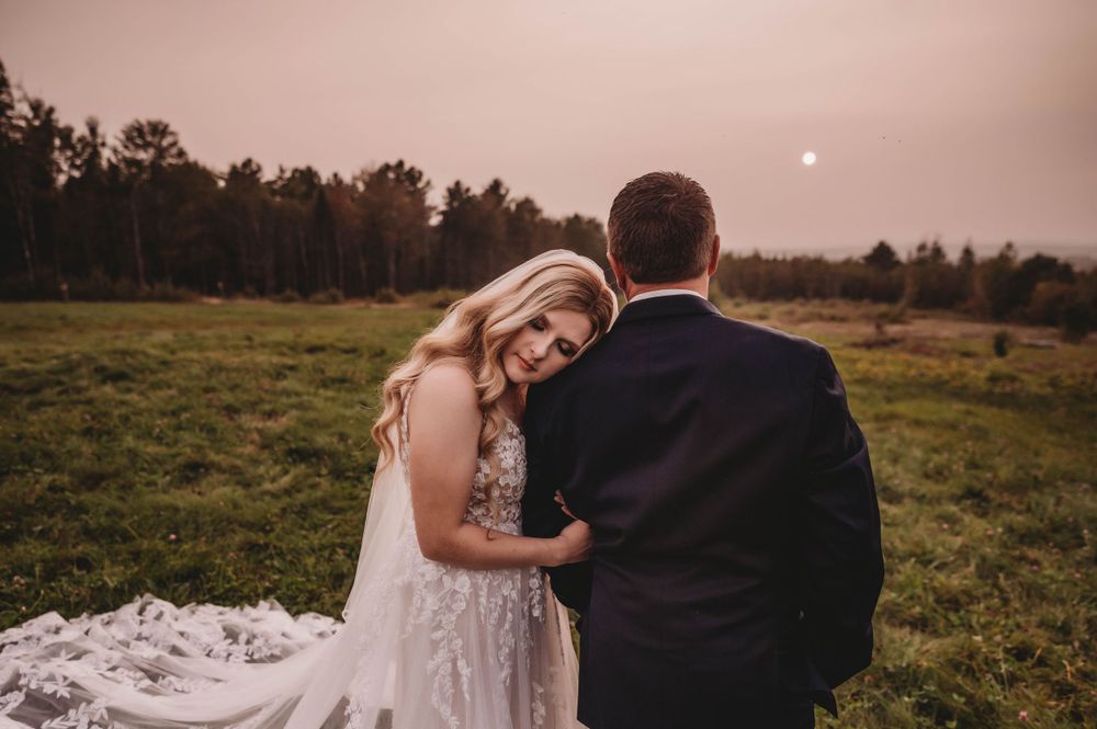 Couple sharing an intimate moment in a field at sunset during their wedding.