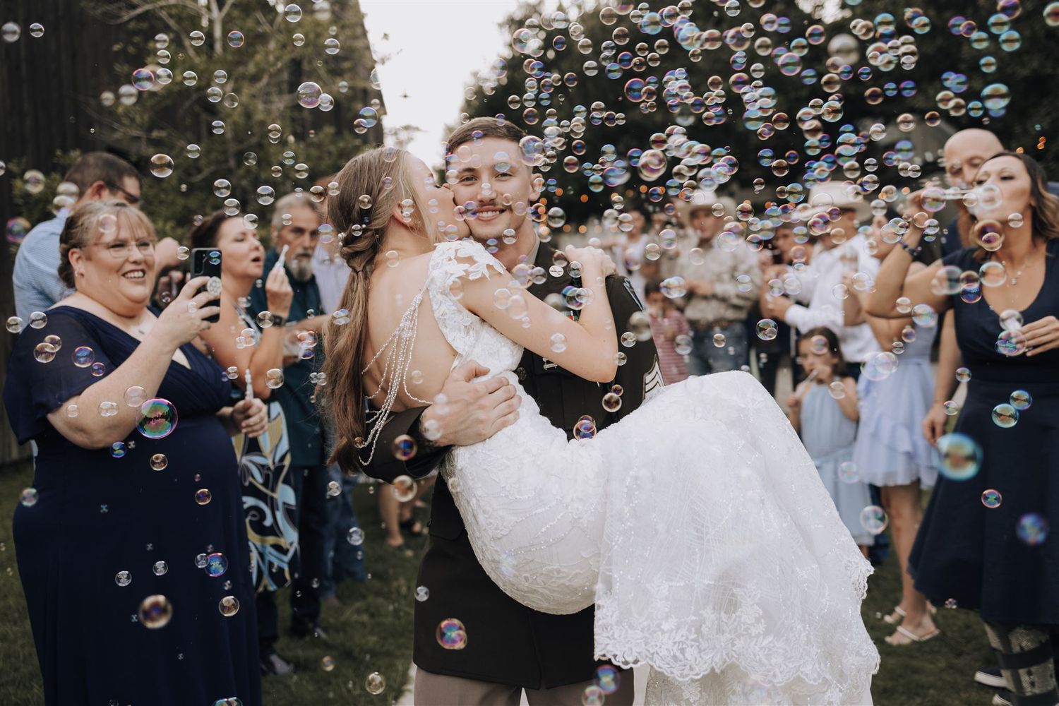 A couple celebrates with a dramatic dip while guests blow bubbles during their wedding exit.