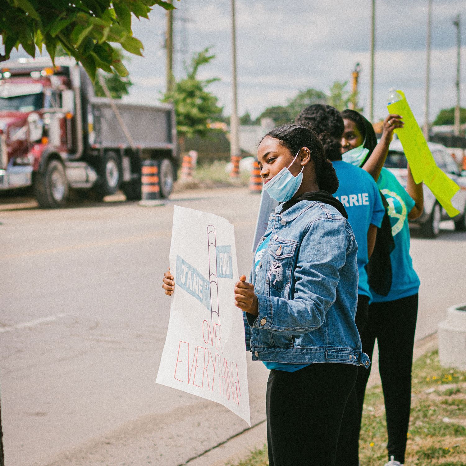 a black folk raising awareness for Finch and Jane community holding a poster, by the street