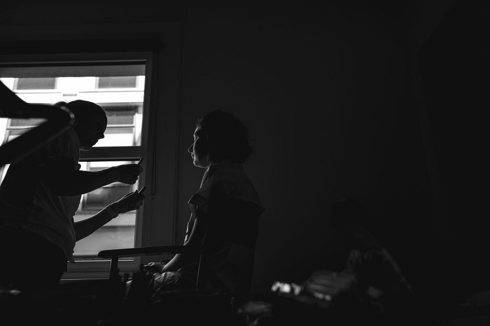 Silhouetted figures working in dark room near window.