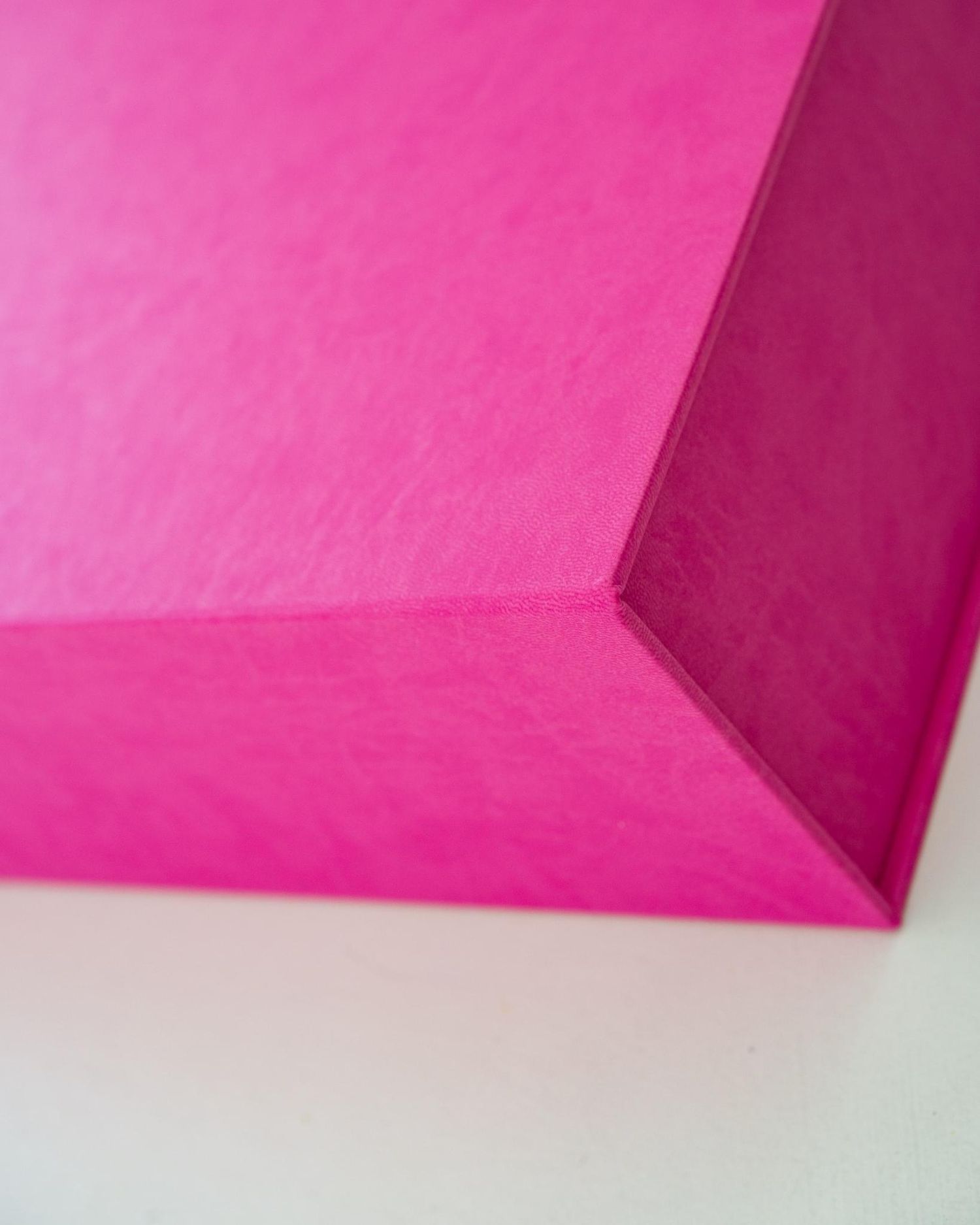 Geometric composition of bright pink surfaces forming an angular shape against white background.