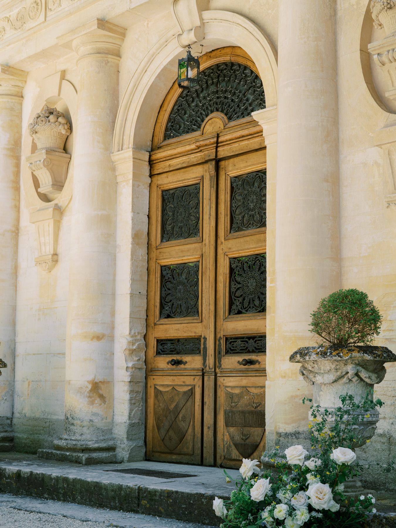Grand ornate doorway with golden doors framed by white columns and roses at the base.