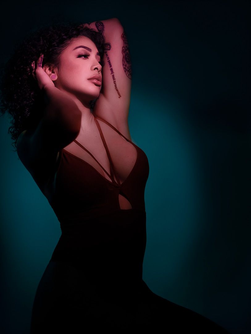Artistic portrait with dramatic lighting against a teal background.