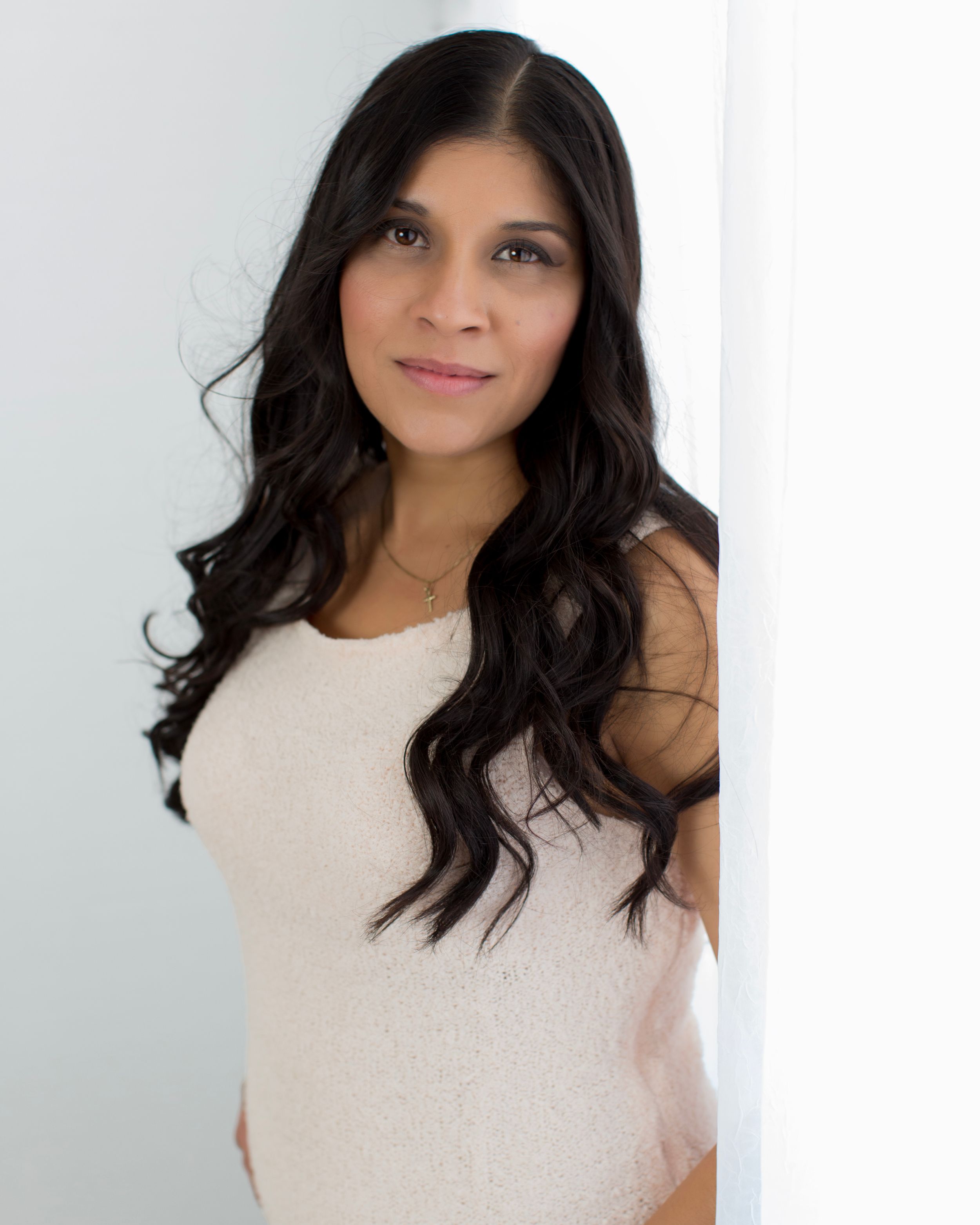 Elegant portrait featuring person in cream colored top with flowing dark hair.
