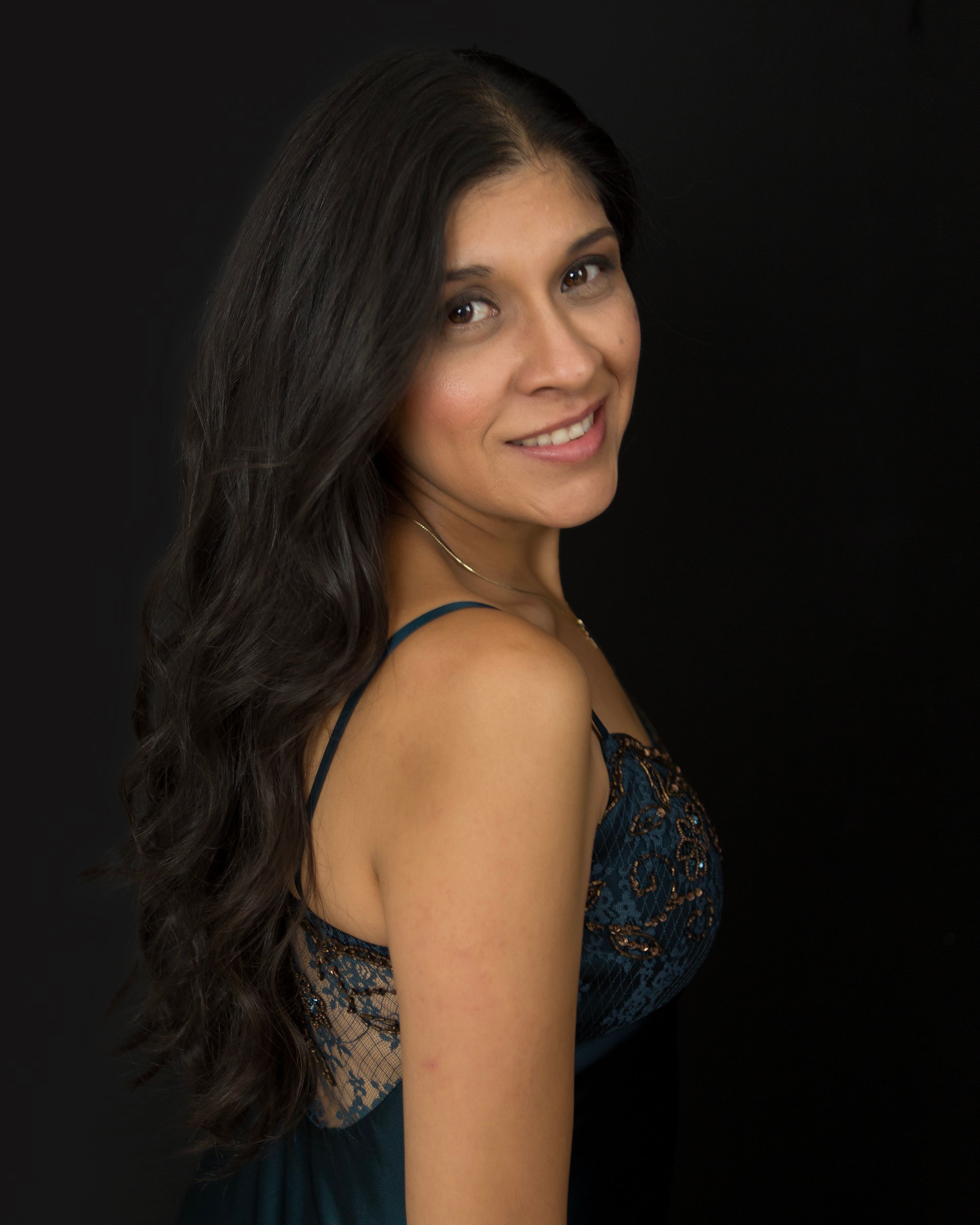 Studio portrait of woman in black sequined dress against dark background.