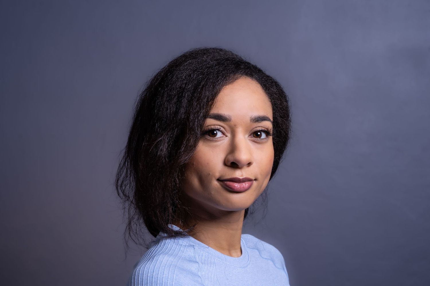 Headshots Brighton and sussex a woman looking to camera in a headshot photography setting wearing a pale blue top and dark hair