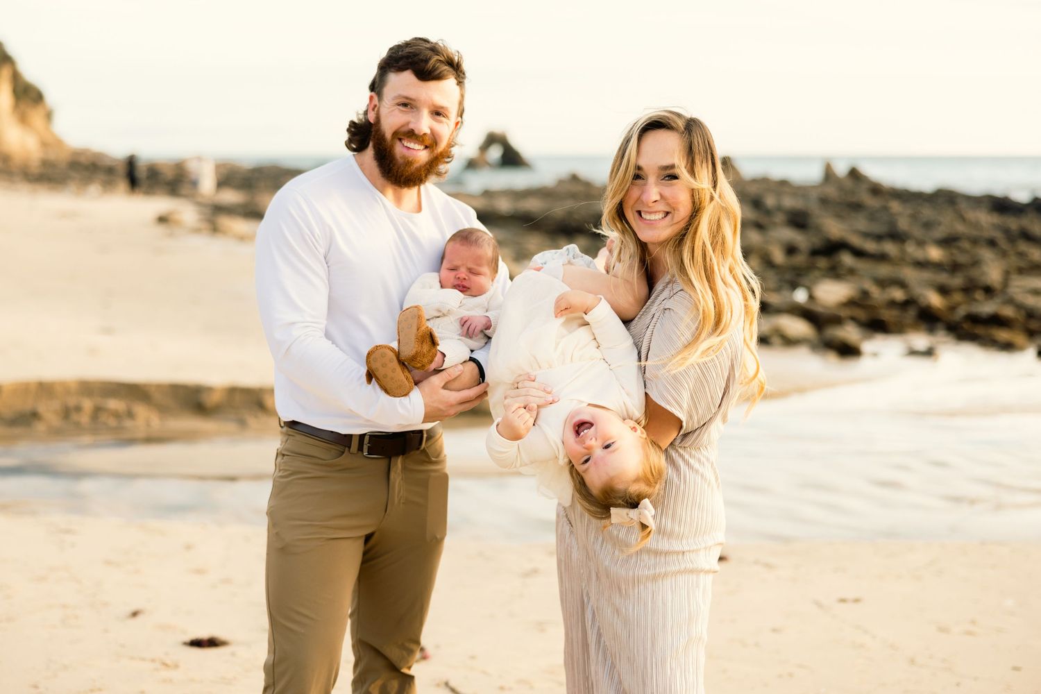 Family enjoying a playful moment together on a sunny beach.