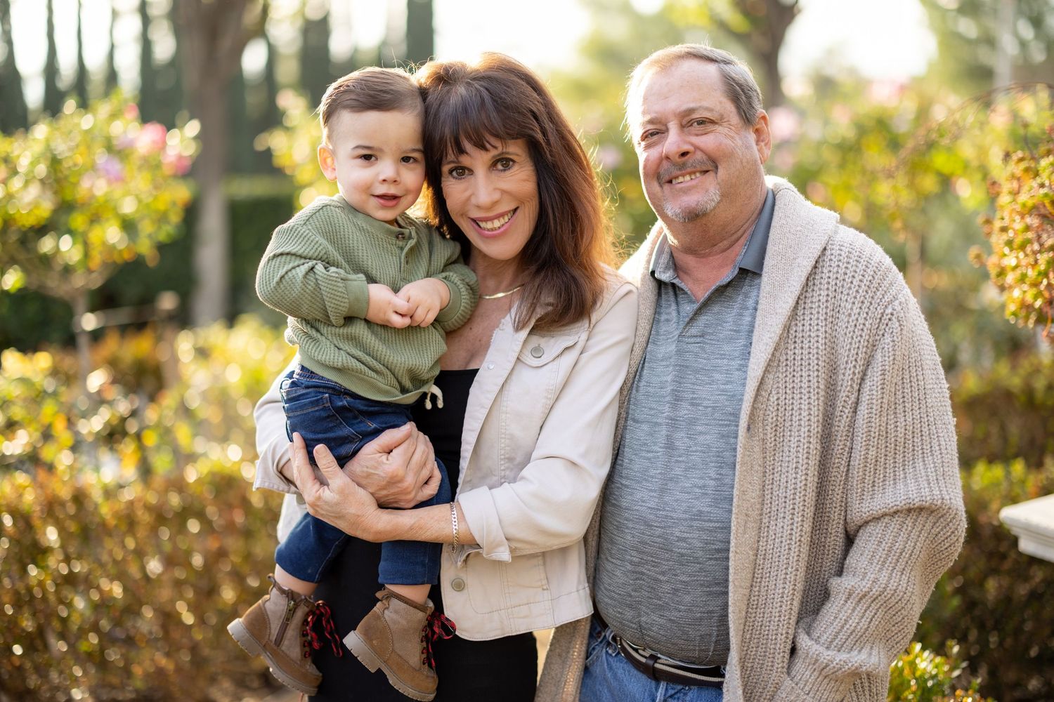 Three generations pose together in an outdoor garden setting.