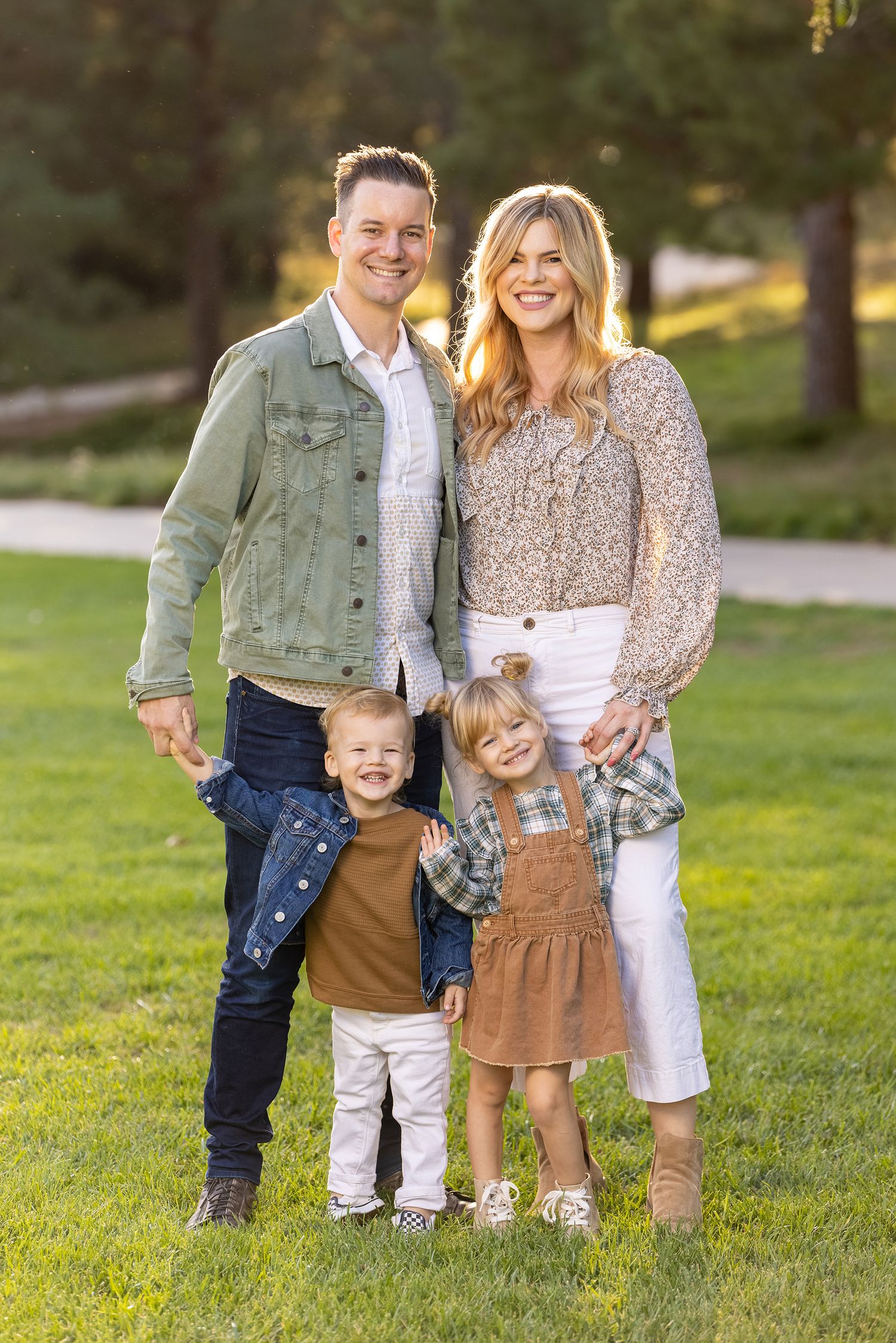Young family poses together on green lawn in coordinated casual outfits.