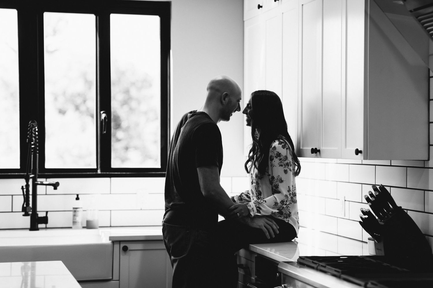 A romantic black and white kitchen scene showing an intimate moment between a couple.
