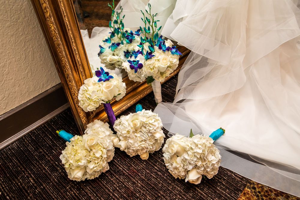 White bridal bouquet with cream roses and blue accents displayed against a textured background.