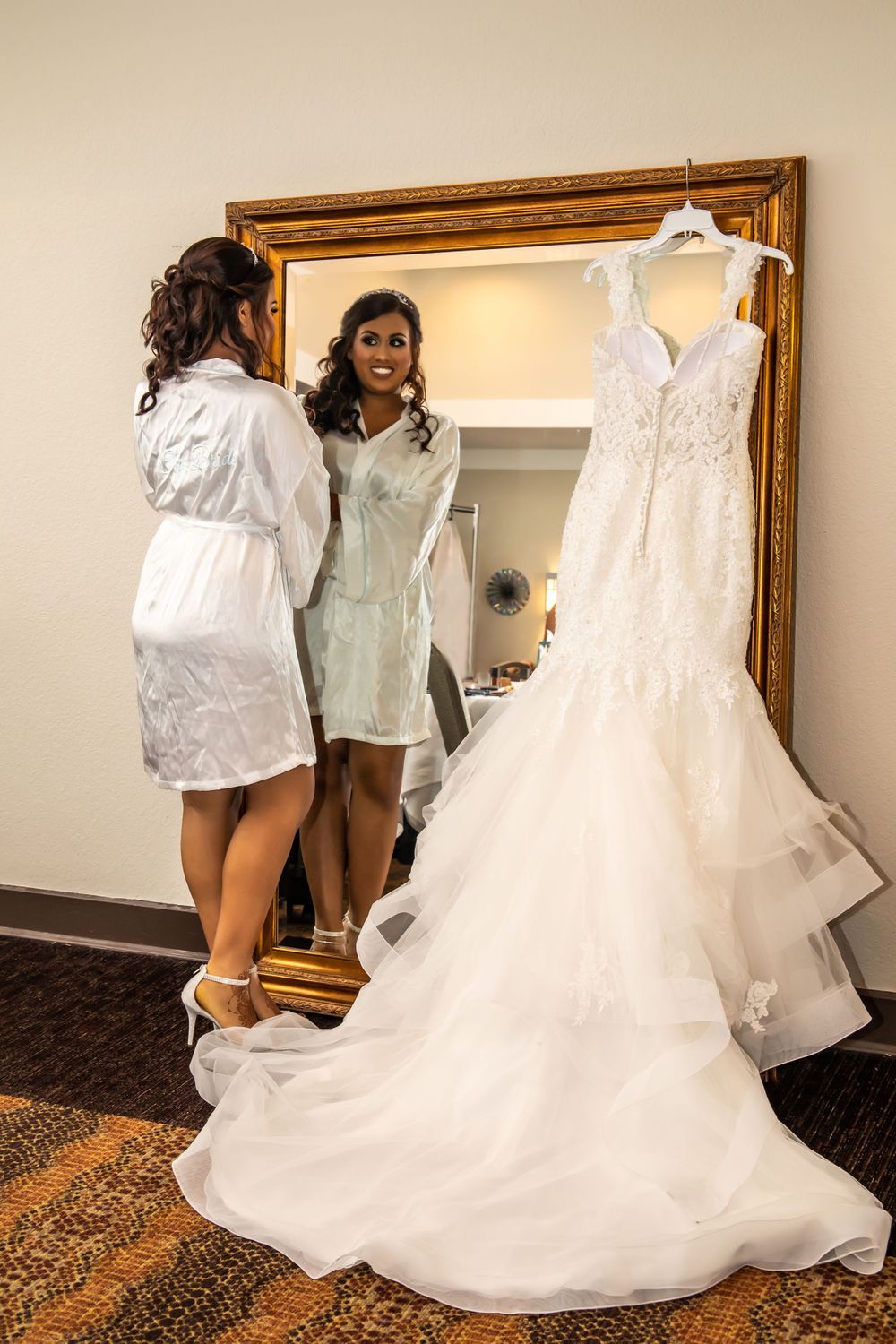 Wedding dress preparation scene with white gowns displayed against wooden-framed mirrors.