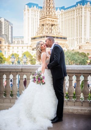Romantic wedding moment captured on balcony with Paris-themed Las Vegas hotel in background.