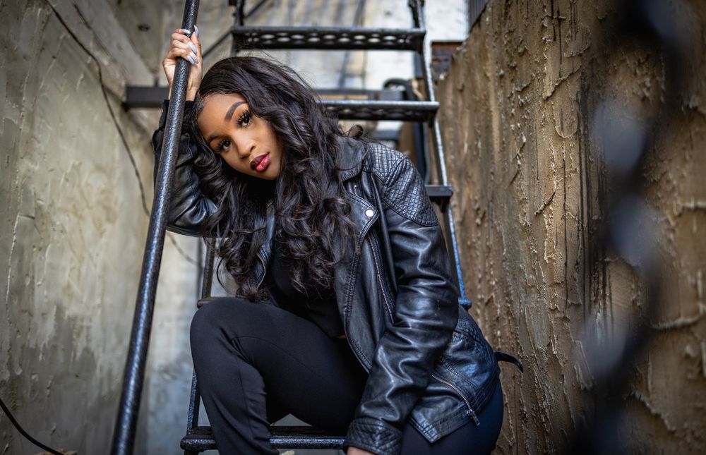 Artistic portrait in urban alleyway with moody lighting and industrial backdrop.